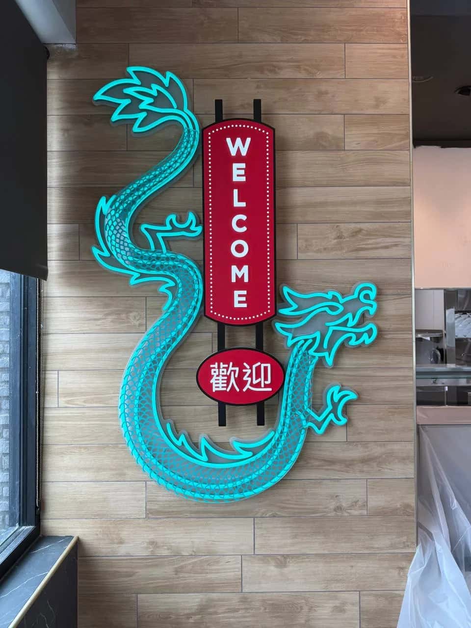 Neon dragon and welcome sign on the panelled wall of a Panda Express dining room