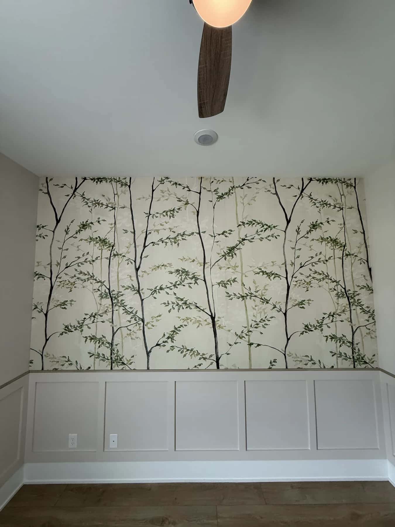 Painted branch wallpaper above panelled wainscot in a dining room