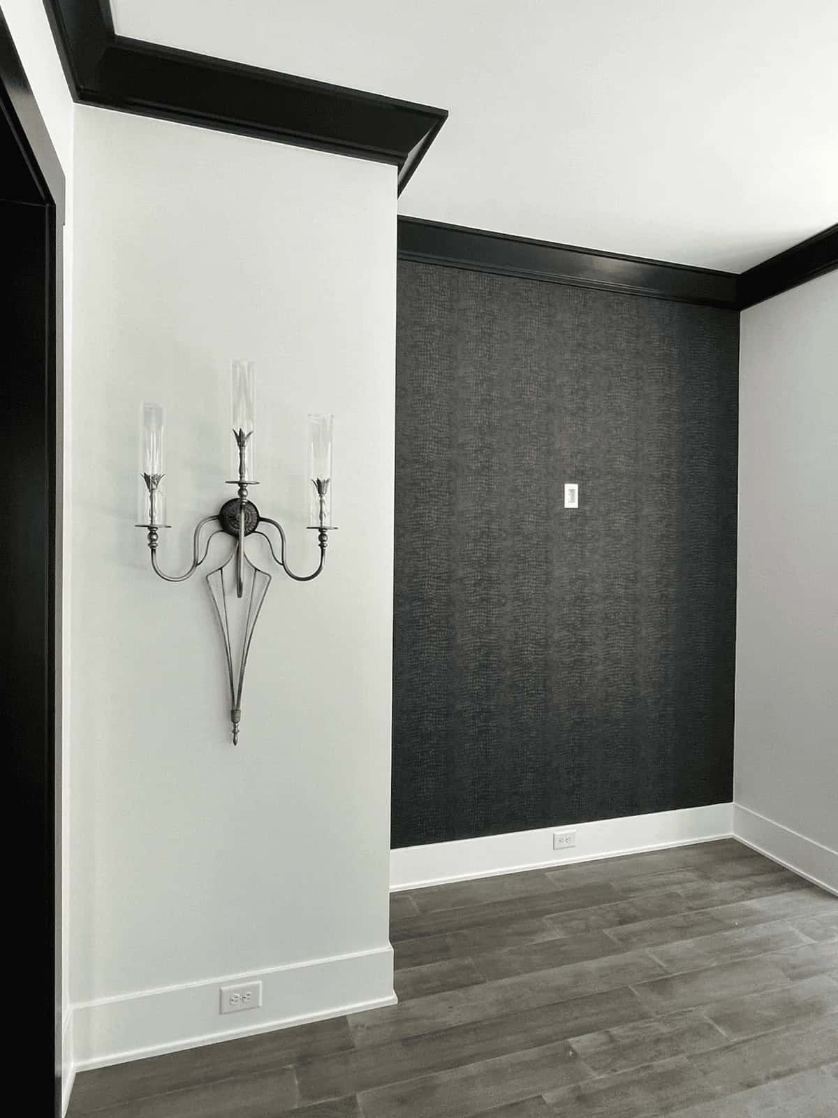 Dark damask wallpaper with a wall sconce
