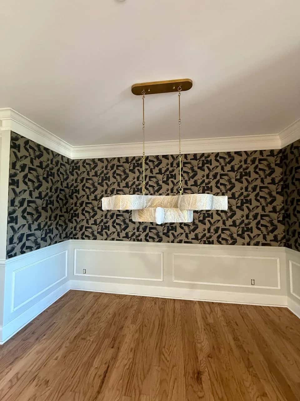 Dark botanical wallpaper above white panelled wainscot in a dining room
