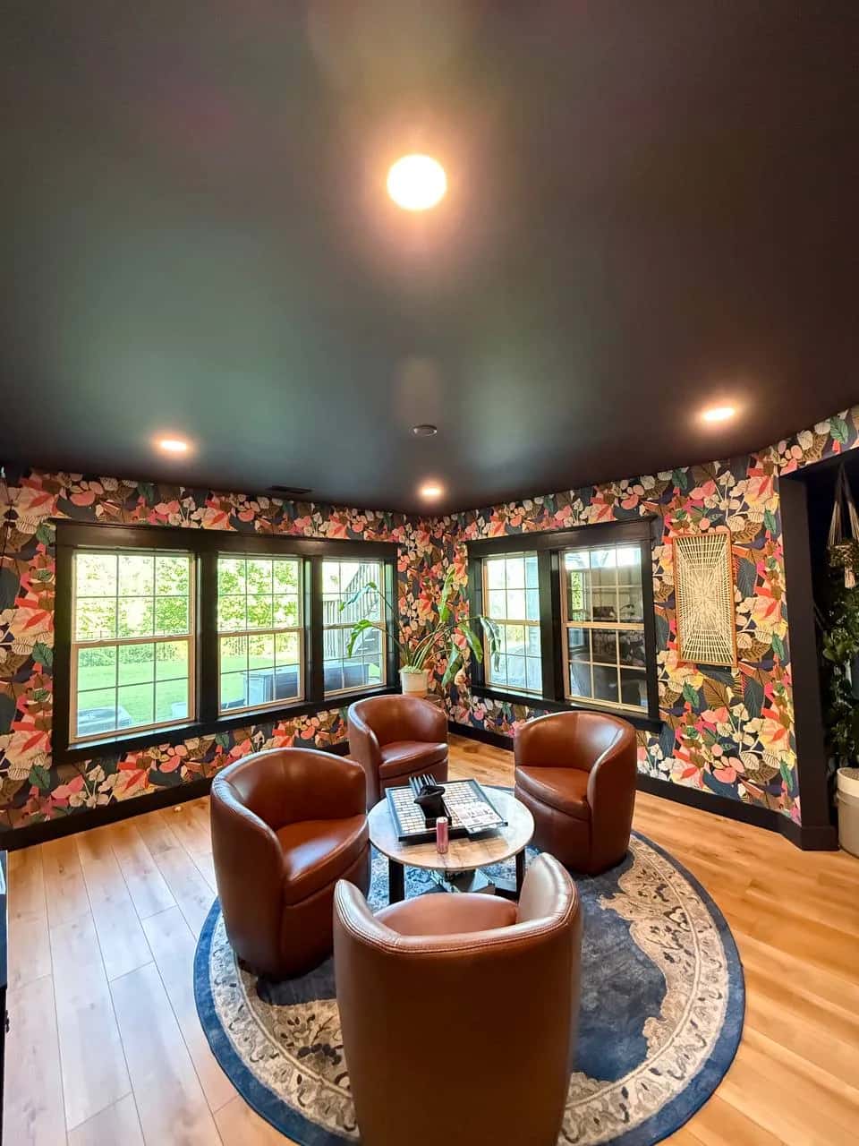 Floral wallpaper and dark painted ceiling in a study