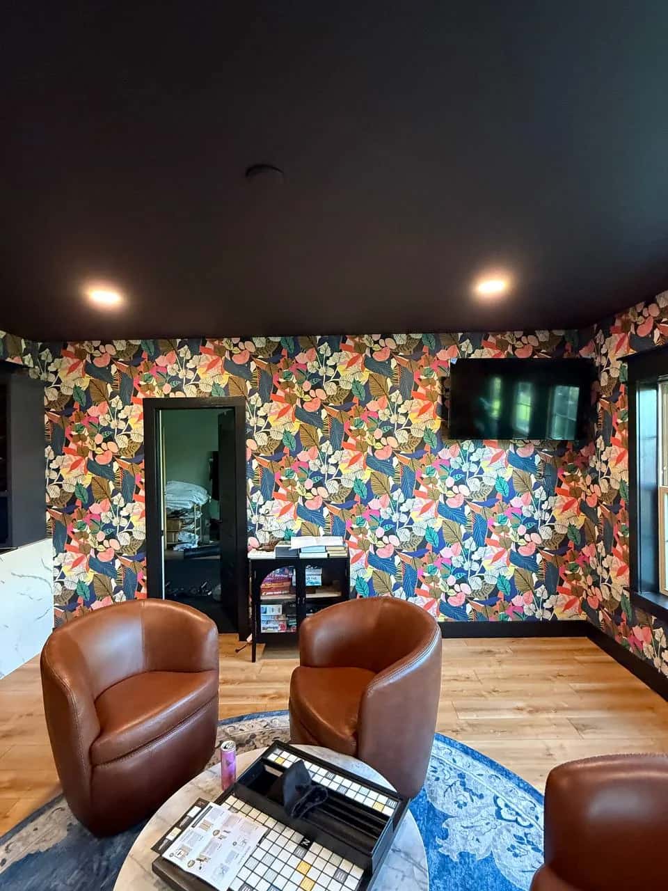 Study with floral wallpaper, leather armchairs and a dark ceiling