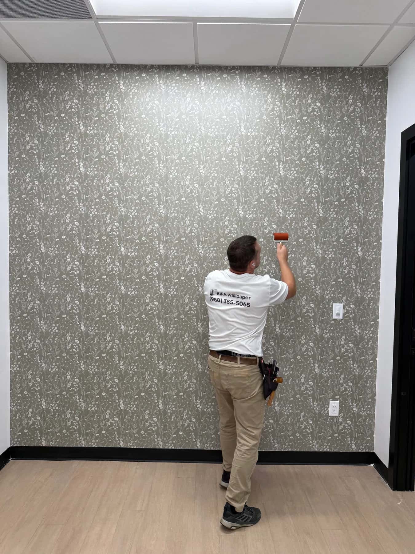 Alex pressing a seam flat with a roller on the wildflower accent wall