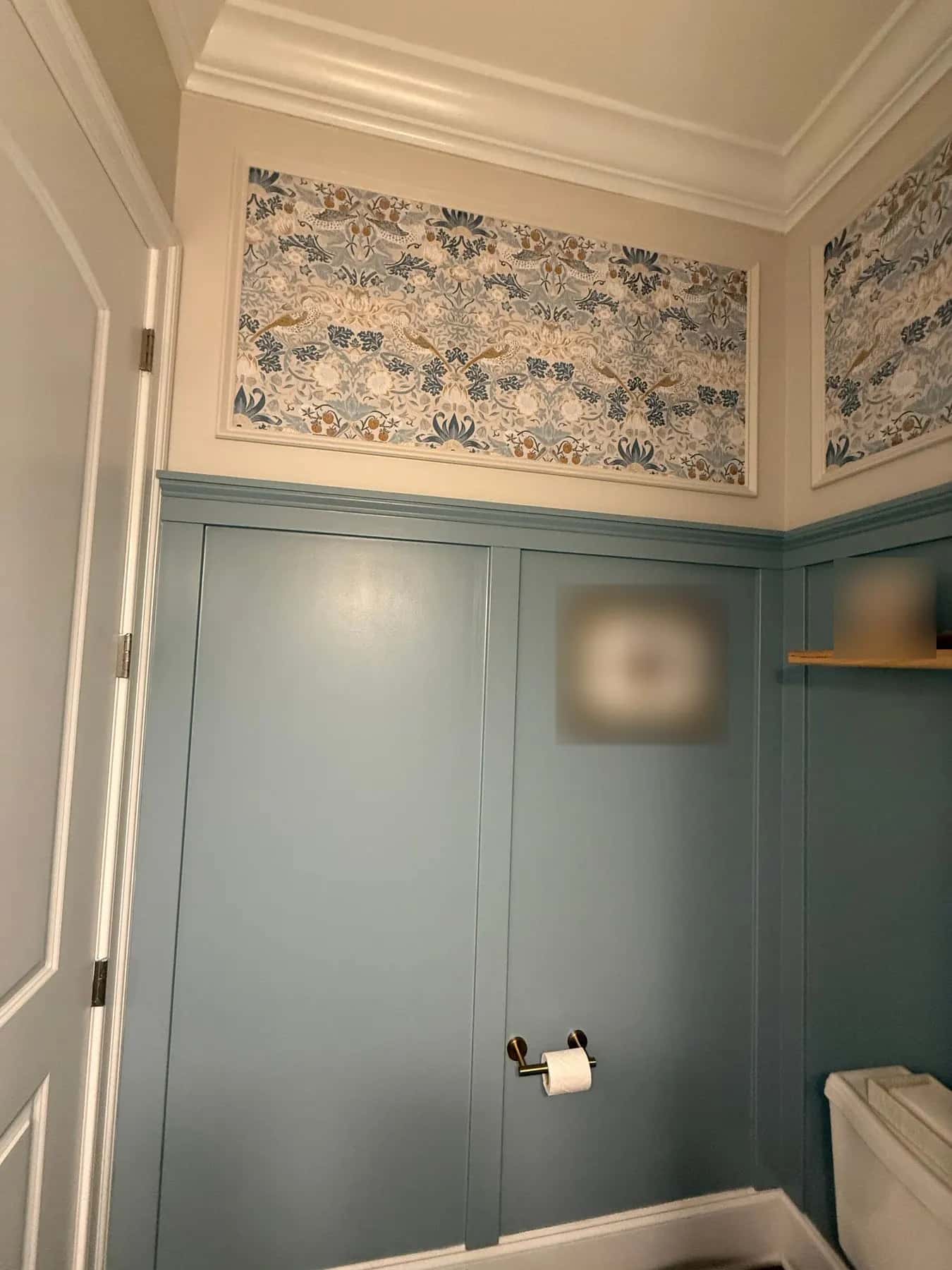 Wide framed wallpaper panel above painted wainscot beside the powder room door