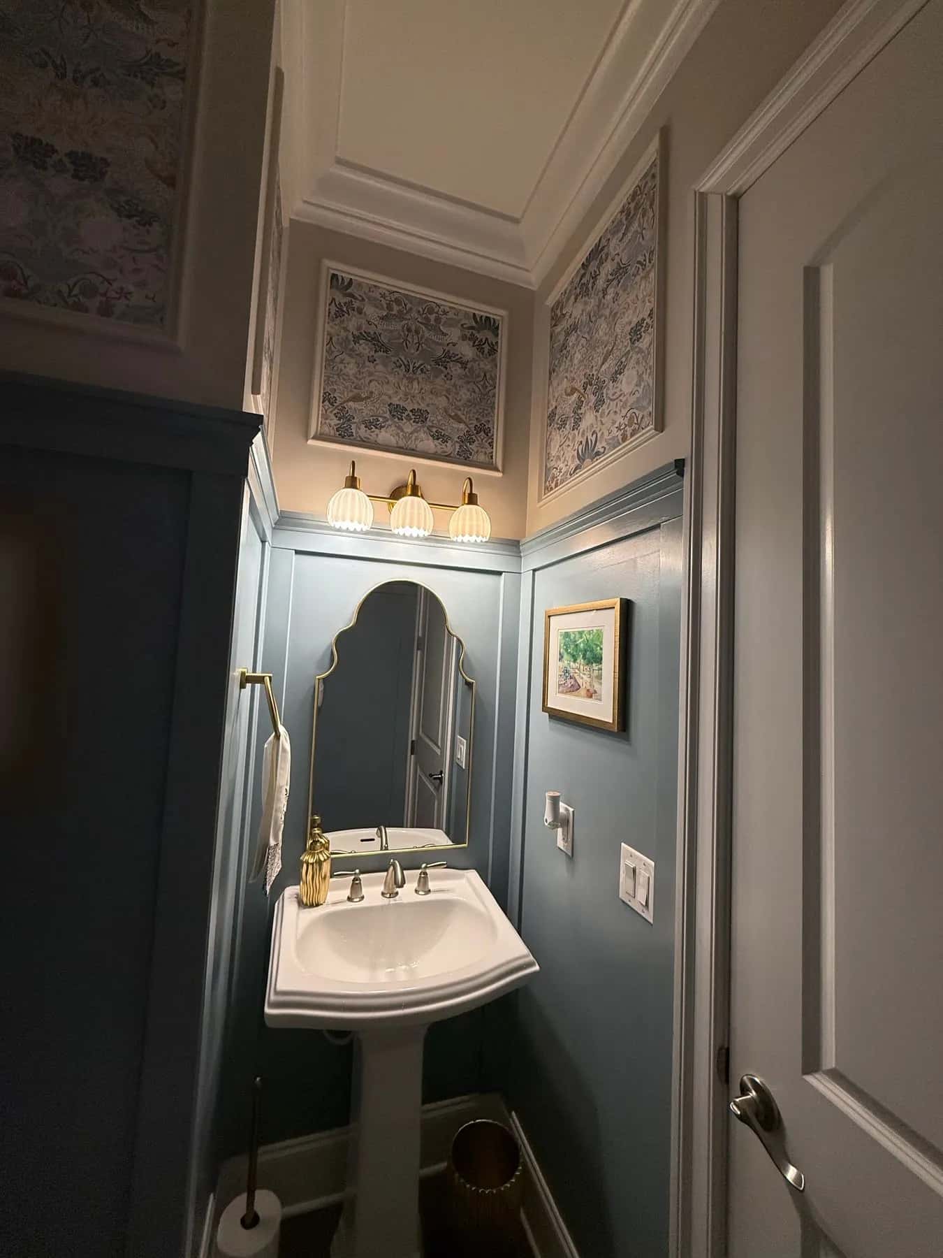Framed wallpaper panels over the vanity seen from the powder room doorway
