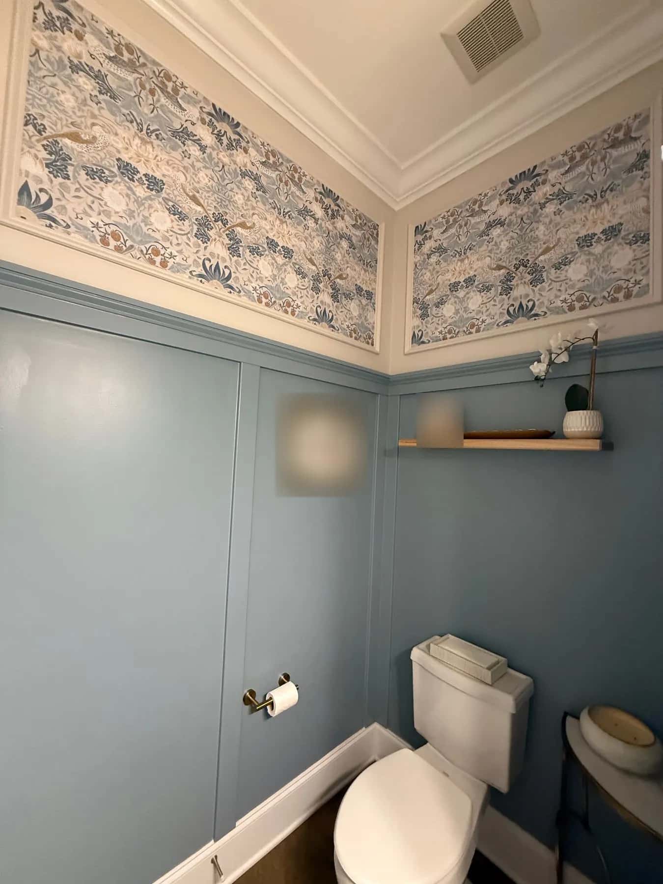 Two long wallpaper panels framed in molding above the wainscot in a powder room