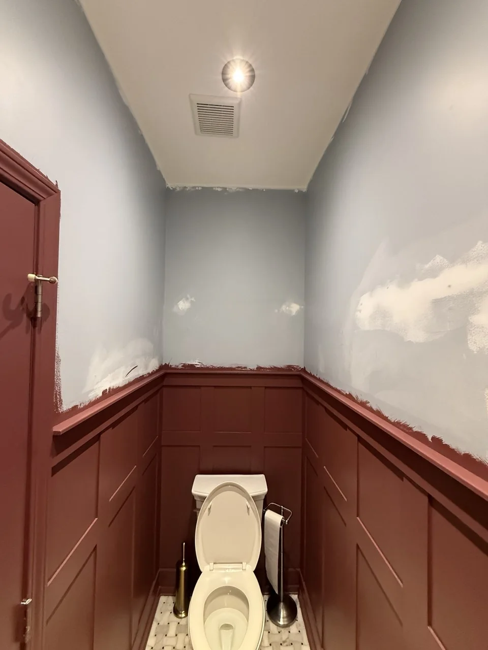 Powder room before papering, plain walls above red wainscot