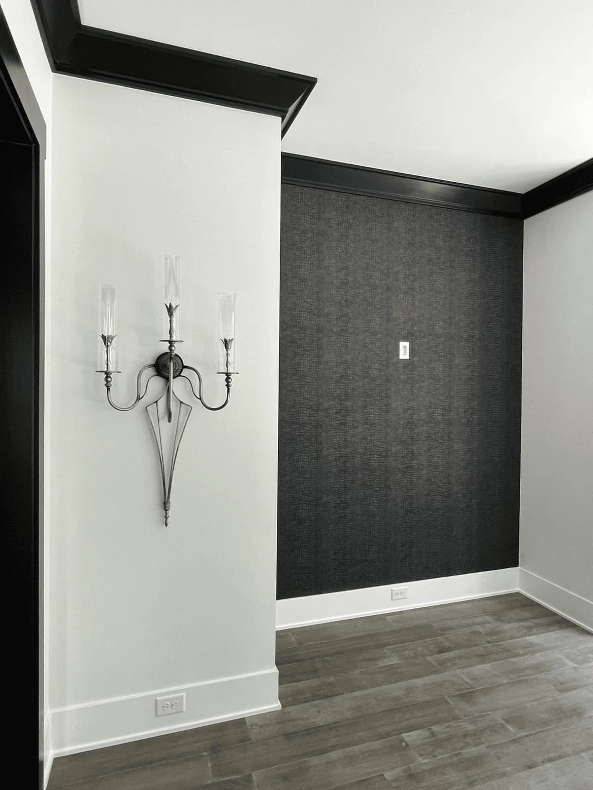 Dark damask wallpaper with a wall sconce