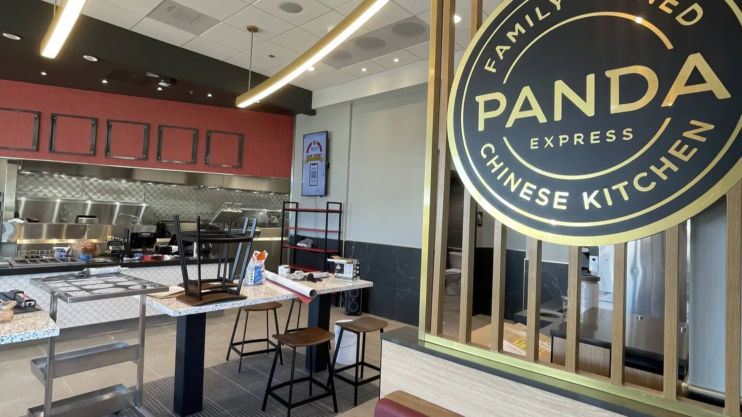 Wallcovering and marble wainscot beside the branded partition of a Panda Express dining room