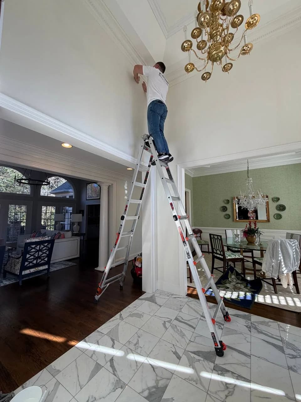 Wallpaper being hung above a staircase from an extension ladder