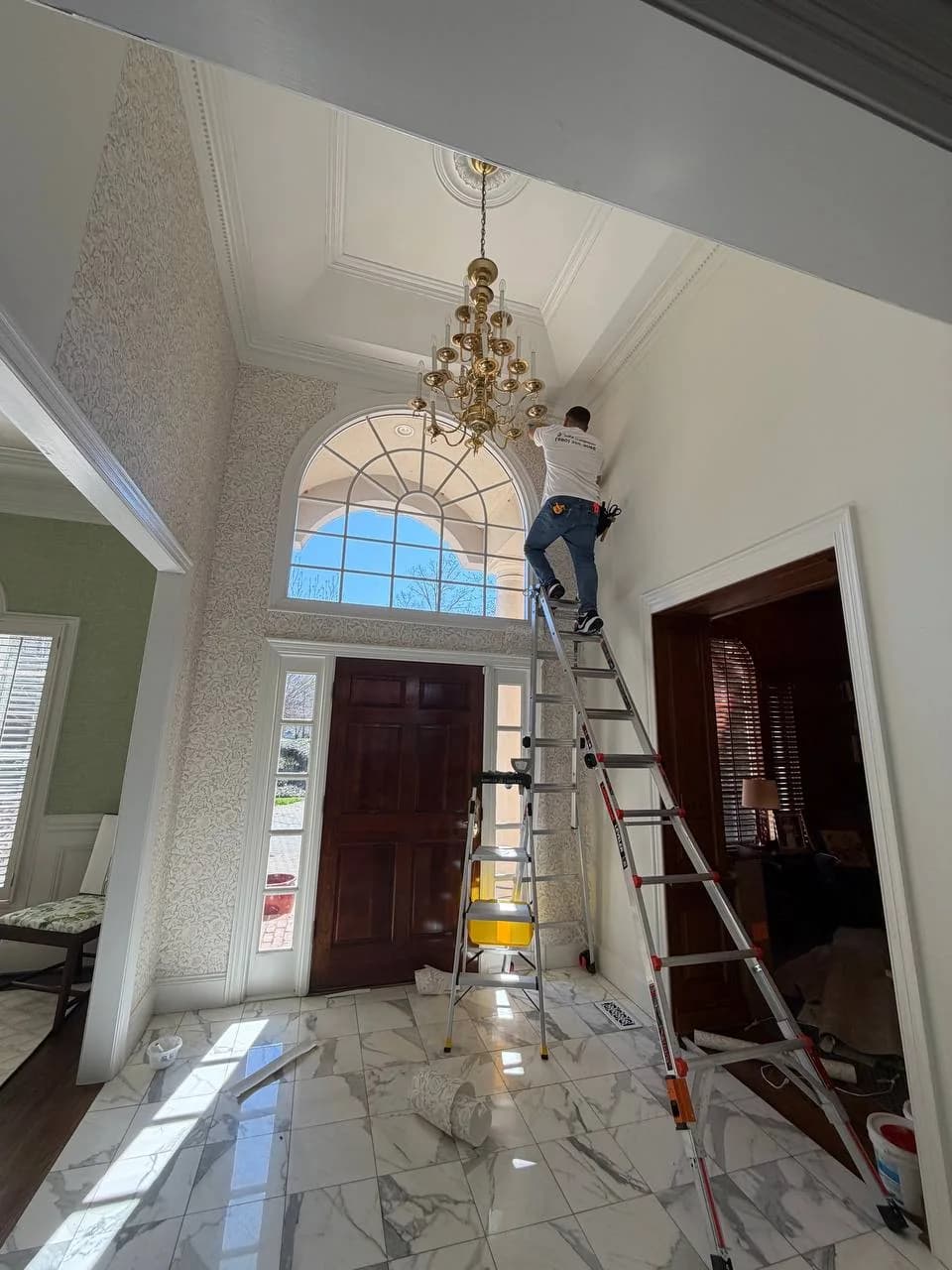 Installer on a ladder papering a two-storey entry foyer